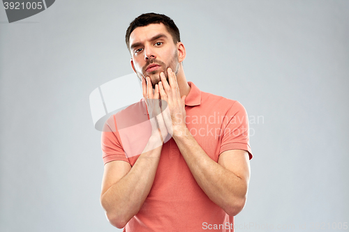 Image of young man touching his face over gray background