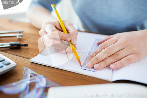 Image of close up of hands with ruler and pencil drawing 