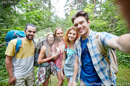 Image of friends with backpack taking selfie in wood