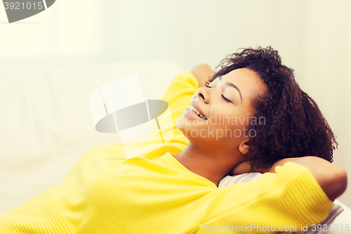 Image of happy african young woman relaxing at home