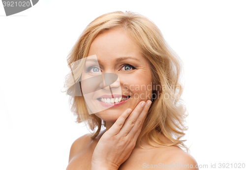 Image of smiling woman with bare shoulders touching face