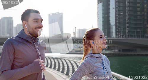 Image of happy couple with earphones running in city