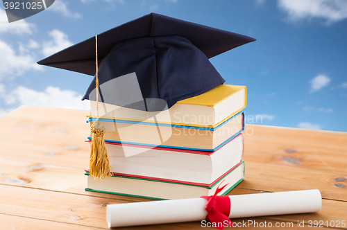 Image of close up of books with diploma and mortarboard