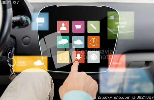 Image of close up of hand and menu icons on car computer