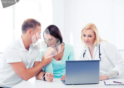 Image of doctor with patients looking at laptop