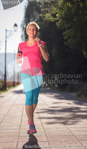 Image of sporty woman running  on sidewalk