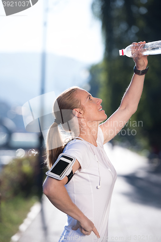 Image of woman drinking  water after  jogging