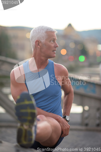 Image of handsome man stretching before jogging