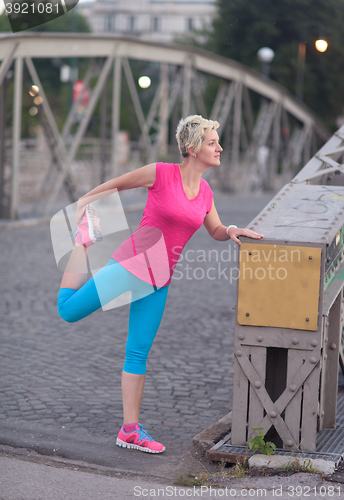 Image of blonde woman  stretching before morning jogging