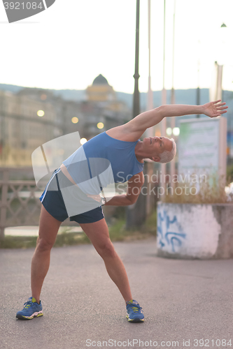 Image of handsome man stretching before jogging