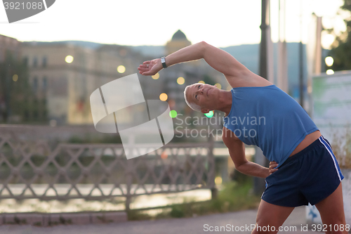 Image of handsome man stretching before jogging