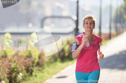 Image of sporty woman running  on sidewalk