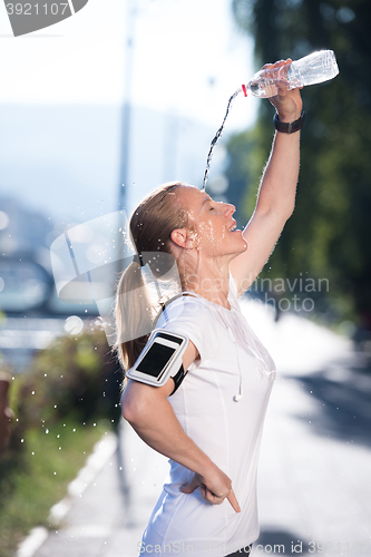 Image of woman drinking  water after  jogging