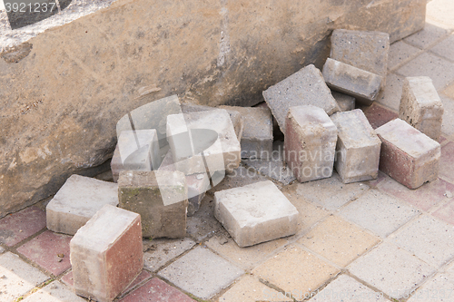 Image of Pieces of old paving slabs lie in a concrete block on the pavement