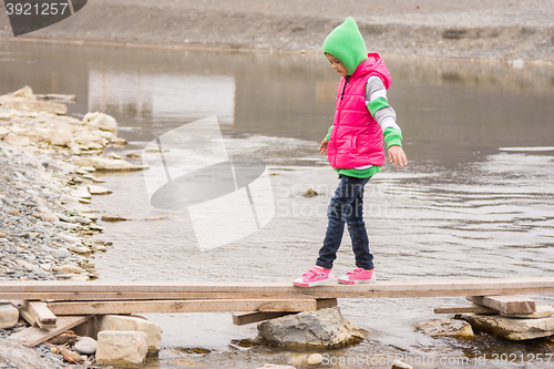 Image of Little girl gently moved across the creek on the board