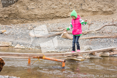 Image of Seven-year girl is gently moved across the creek on the makeshift bridge