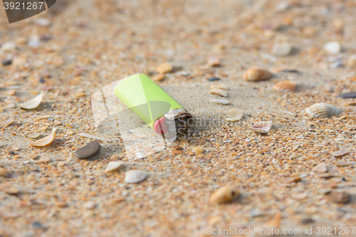 Image of Old used lighter in the sand on the beach