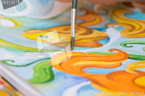 Image of Drawing on paper with watercolor brush closeup