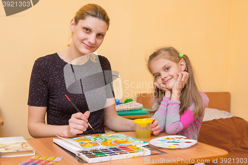 Image of a drawing teacher teaches a little girl paint watercolors