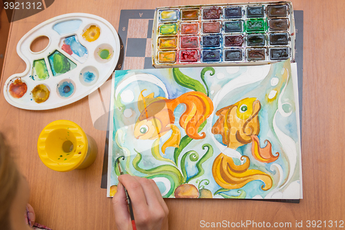 Image of Top view of the process of drawing on watercolor paper goldfish