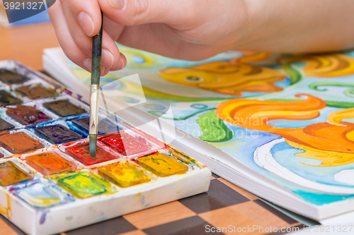 Image of Close-up of the hand of the artist with a brush recruited watercolor paint