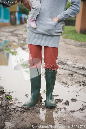 Image of woman in rubber boots standing in a puddle