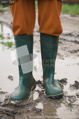 Image of woman in rubber boots standing in a puddle