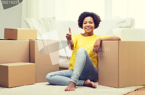 Image of happy african woman with cardboard boxes at home