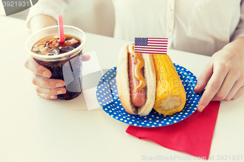 Image of close up of woman eating hot dog with cola