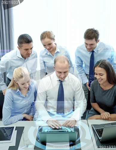 Image of smiling business people with laptop in office