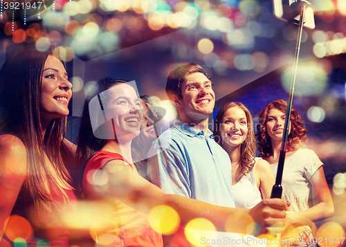 Image of friends with smartphone taking selfie in nightclub