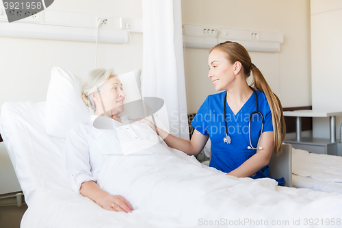 Image of doctor or nurse visiting senior woman at hospital