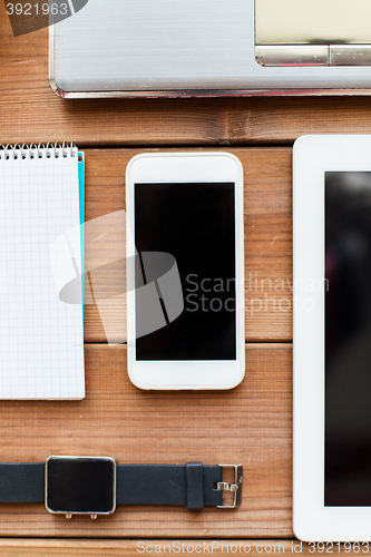 Image of close up of smartphone and smartwatch on table