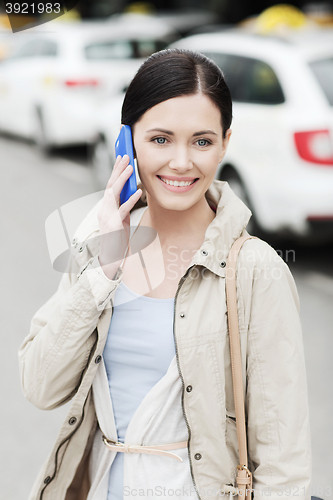 Image of smiling woman with smartphone over taxi in city