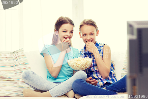 Image of happy girls with popcorn watching tv at home