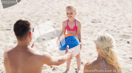 Image of happy family playing with inflatable ball on beach