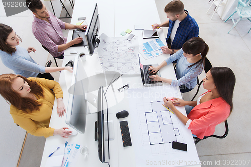 Image of creative team with computers, blueprint at office