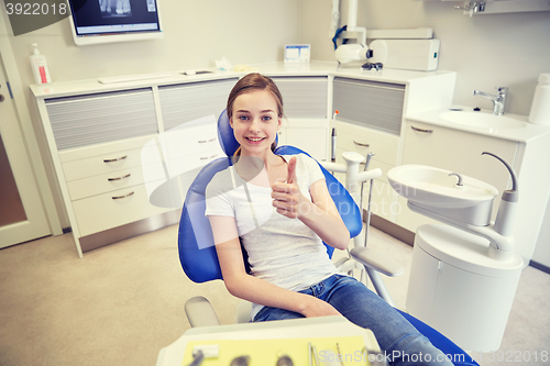 Image of happy patient girl showing thumbs up at clinic