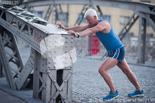 Image of handsome man stretching before jogging