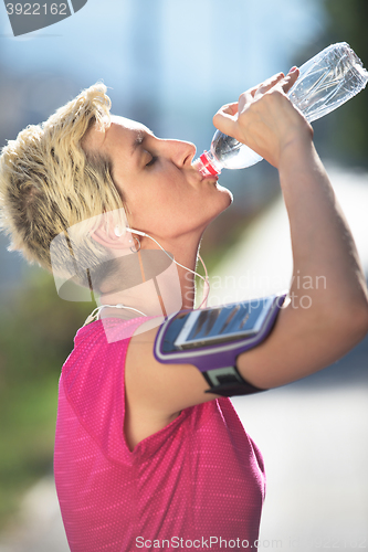 Image of woman drinking  water after  jogging