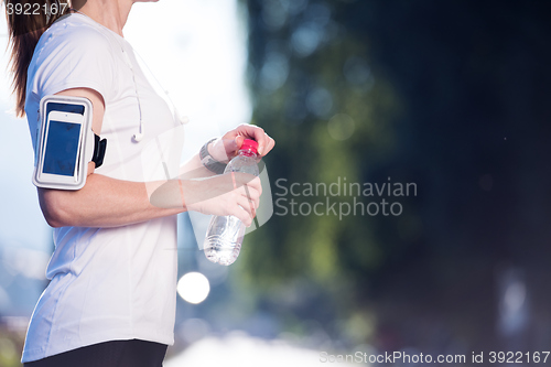 Image of woman drinking  water after  jogging