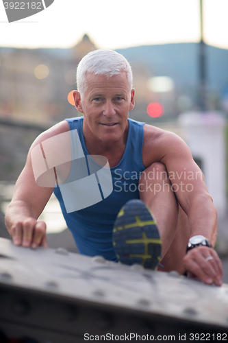 Image of handsome man stretching before jogging