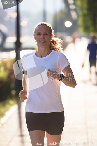 Image of sporty woman running  on sidewalk