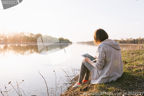 Image of girl working with tablet at the river