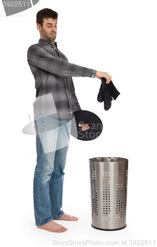 Image of Young man putting a dirty socks in a laundry basket