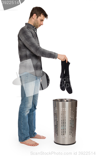 Image of Young man putting a dirty socks in a laundry basket