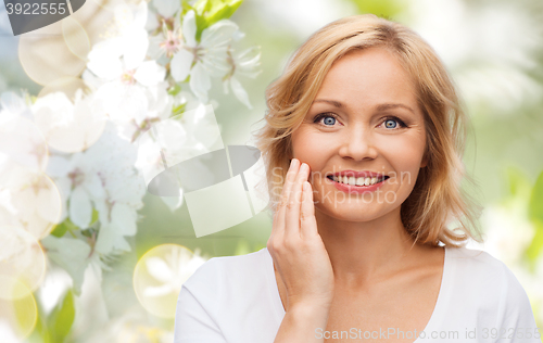 Image of smiling woman in white t-shirt touching her face