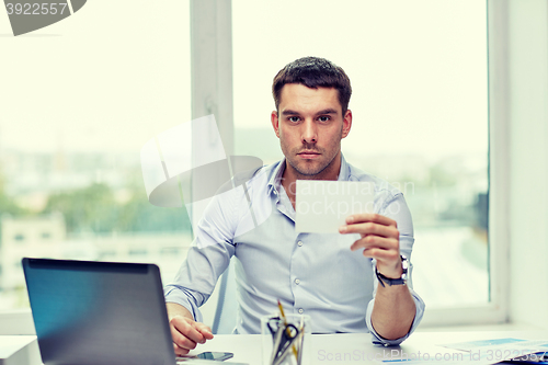 Image of businessman showing blank paper card at office