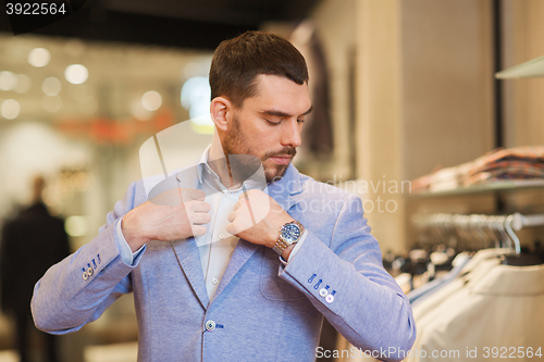 Image of young man trying jacket on in clothing store