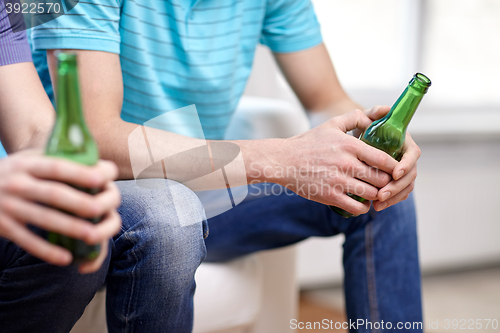 Image of close up of male friends drinking beer at home